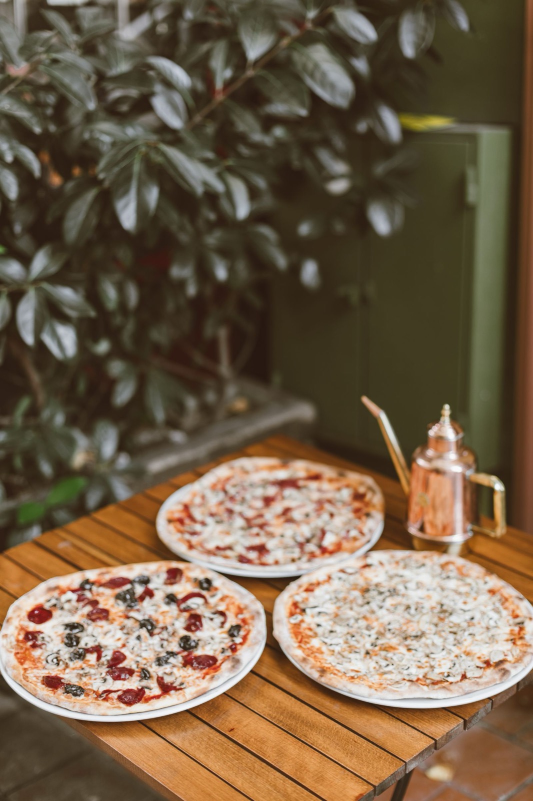 Tre hjemmelagde pizzaer på et hagebord